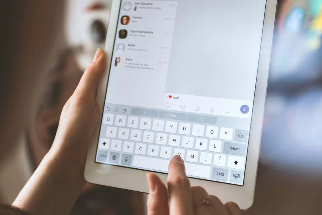 person using white iPad chat bot builders